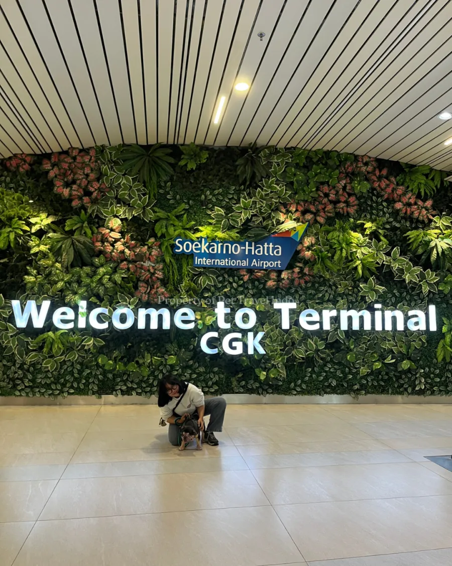 Pet Travel Indo team member with a dog in front of the Welcome to Terminal CGK sign at Soekarno-Hatta airport